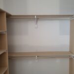 Two-tier closet shelving with particle board shelves, 1x4 cleats, and white support brackets installed.