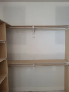Unfinished closet shelving with particle board shelves on wood cleats and white support brackets