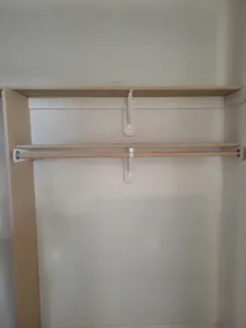 Closet shelf and hanging rod mounted on white support brackets against a plain painted wall.