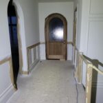 Hallway with installed casing, baseboard, and arched door opening ready for paint.