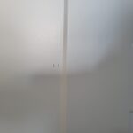 Installed mullion strip dividing two wall sections, painted white with nail holes visible.