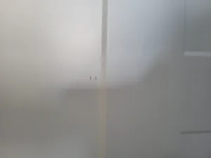 Painted white wall corner seam with a couple of small holes visible.