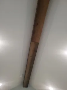 Dark stained wood beam spanning a vaulted ceiling at a dramatic diagonal angle