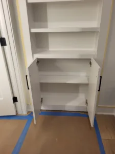 Painted built-in cabinet with open shelves and lower cabinet doors installed in a closet opening
