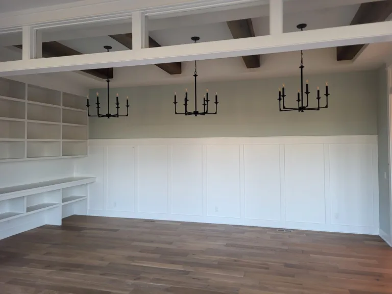 Elegant living room with wainscoting, built-in shelving, and wood beams.