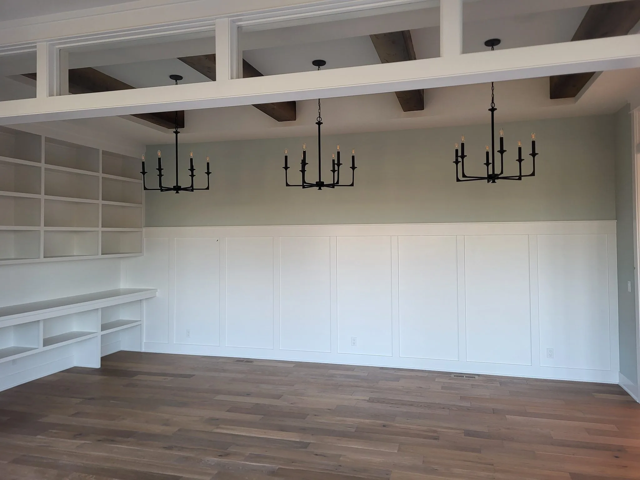 Elegant living room with wainscoting, built-in shelving, and wood beams.