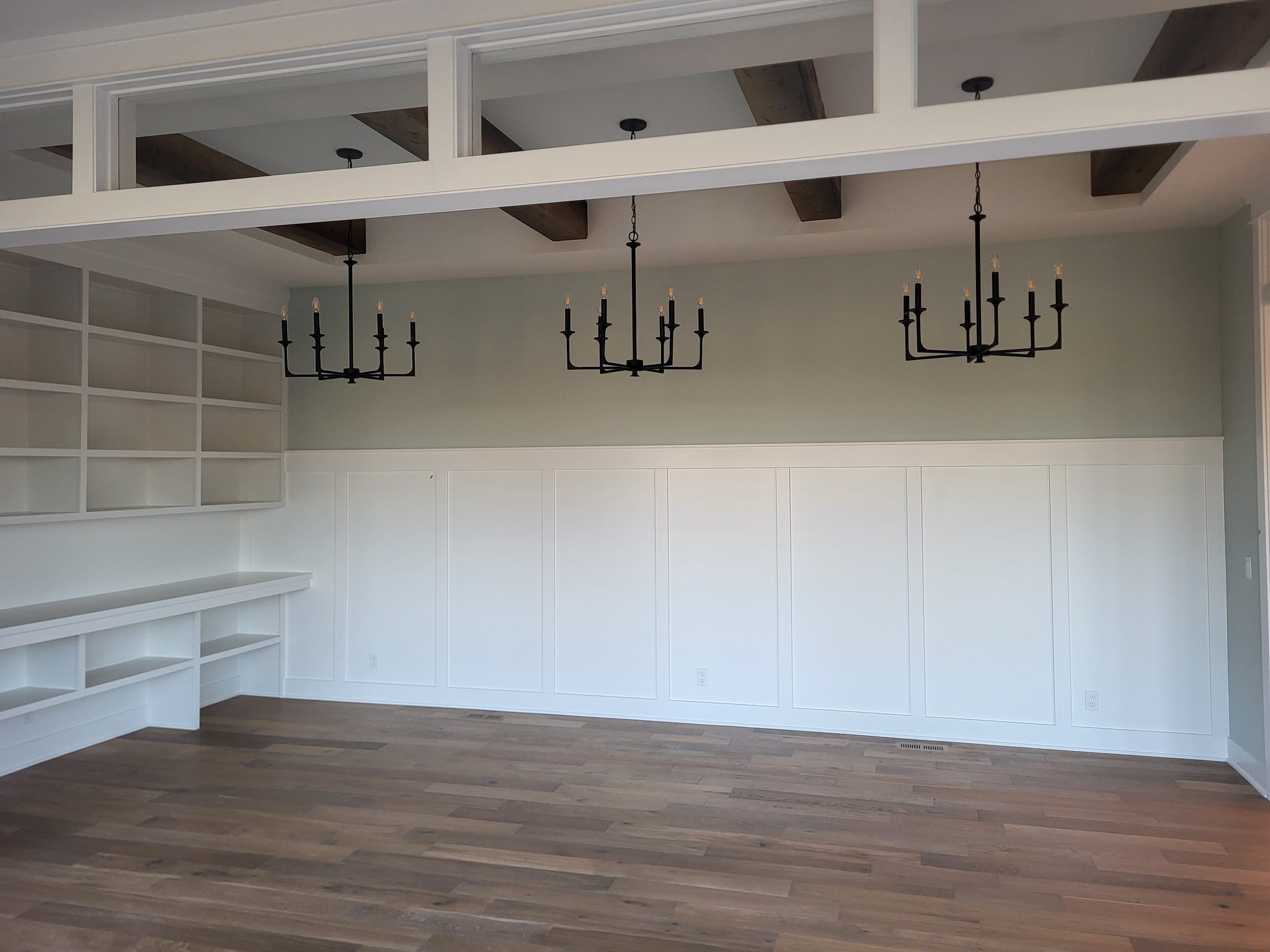 Elegant living room with wainscoting, built-in shelving, and wood beams.