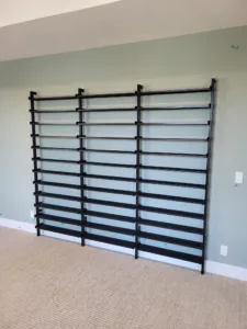 Finished black horizontal-bar wall panels mounted on a painted wall above carpet flooring.