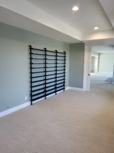Black horizontal slat wall feature installed on a finished wall with painted trim and carpet flooring