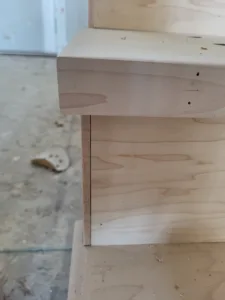 Unfinished wood corner joint with drilled fastener holes, raw construction detail