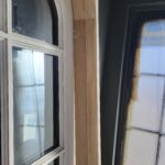 Window jamb extensions installed to bring jambs flush with thick wall; raw wood stain visible before painting.