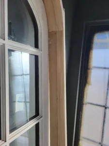 Raw wood jamb extensions installed on an arched window, unpainted and ready for trim