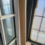 Vertical wood mullion strip installed between two adjacent window units with white frames.