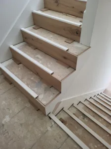 Wood grain stair treads with painted white risers along a staircase wall