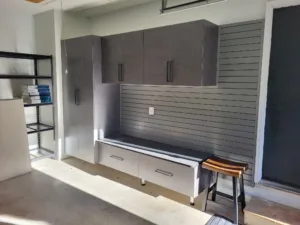 Garage cabinet wall with gray upper cabinets, ribbed center panel, and lower storage bench, complete.