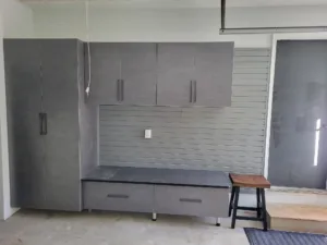 Garage cabinets with gray upper units, slatwall panel, and lower storage bench, installed.