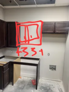 Kitchen during construction with dark stained cabinets installed and an area circled for reference.