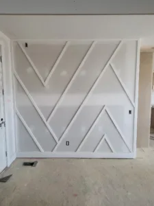 Chevron pattern accent wall with applied wood strips, primed white and ready for final paint