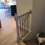 Painted newel post with metal handrail and iron balusters at stair landing.