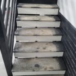 Garage stairs with 2 stringers and closed risers—raw wood treads, black risers, white riser boards, fasteners visible, ready for paint.