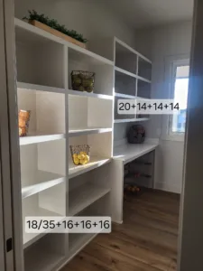 Open built-in shelving unit with cubbies and a work counter in a pantry or closet space.