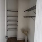 Completed walk-in closet with wire shelving, hanging rods, and painted walls ready for use.