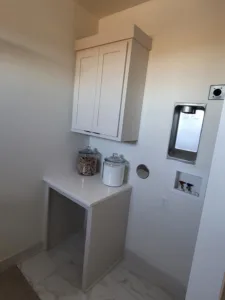 Painted white wall cabinet with two doors mounted above a small countertop nook, fully installed.