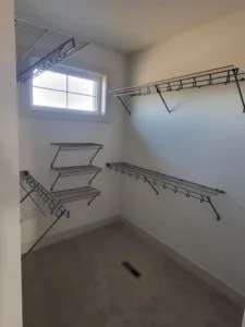 Wire shelving and hanging rods installed in a closet with painted walls and a window