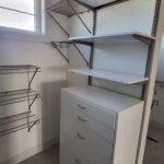 Closet shelving system with painted shelves, metal brackets, and hanging rod installed.