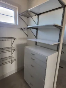 Wire closet shelving with a wood shelf above a white four-drawer storage unit, window nearby.
