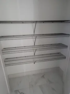 White wire shelving installed in closet with four tiers and support brackets, tile floor visible.