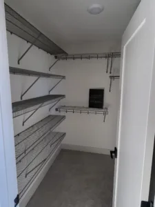 Wire closet shelving with multiple tiers mounted on painted gray walls, white door and ceiling light.