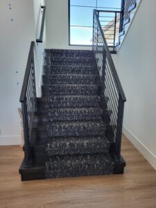 Completed staircase with carpeted treads, finished risers, and metal handrails installed.