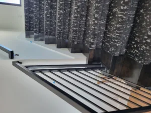 Closeup of a stairway with dark patterned carpet treads and a white stringer edge