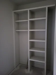 White face frame closet shelving with vertical dividers and multiple shelves installed in a wall recess.