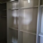 Custom built-in closet shelving with white-finished wood frame, multiple shelves, and compartments ready for paint.