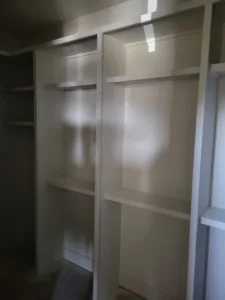 White painted closet shelving with multiple vertical dividers and open compartments installed.