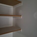 Standard closet shelves painted brackets installed on white wall.