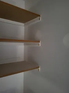 Closet shelves in a light wood tone resting on white painted brackets, mounted on the wall