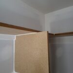 Wood rail and backing panel installation in progress at interior corner with drywall.