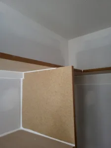 Wood rail and particle board backing panel being installed at an interior corner, work in progress.