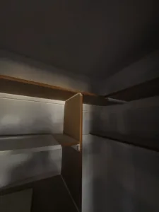 Closet shelving corner with a wood divider bulkhead separating two shelf compartments