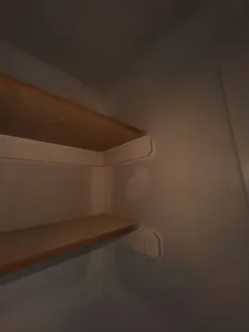 Closet corner shelf with a wood-tone finish and a white support bracket installed