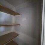 Four-shelf closet unit with stained wood shelves and white support brackets, ready for paint or final finishing.