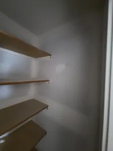 Four wood closet shelves with white support brackets installed, ready for final finishing.