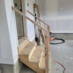 This photo shows the installation of a temporary handrail on garage steps, indicating ongoing work in progress.