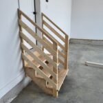 This photo shows a mid-installation view of a wooden handrail for garage steps, highlighting the framework and design details.