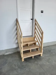 Garage stair with three open treads up to a house door, slat rails on both open sides, raw wood