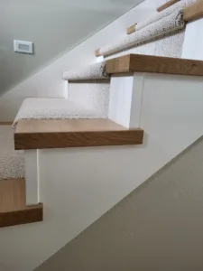 Carpeted stair treads with wood nosing caps, a glass panel railing visible along the stairwell