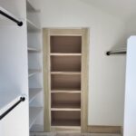 Face-frame closet shelving unit with five shelves, natural wood frame, and brown backing installed in walk-in closet.